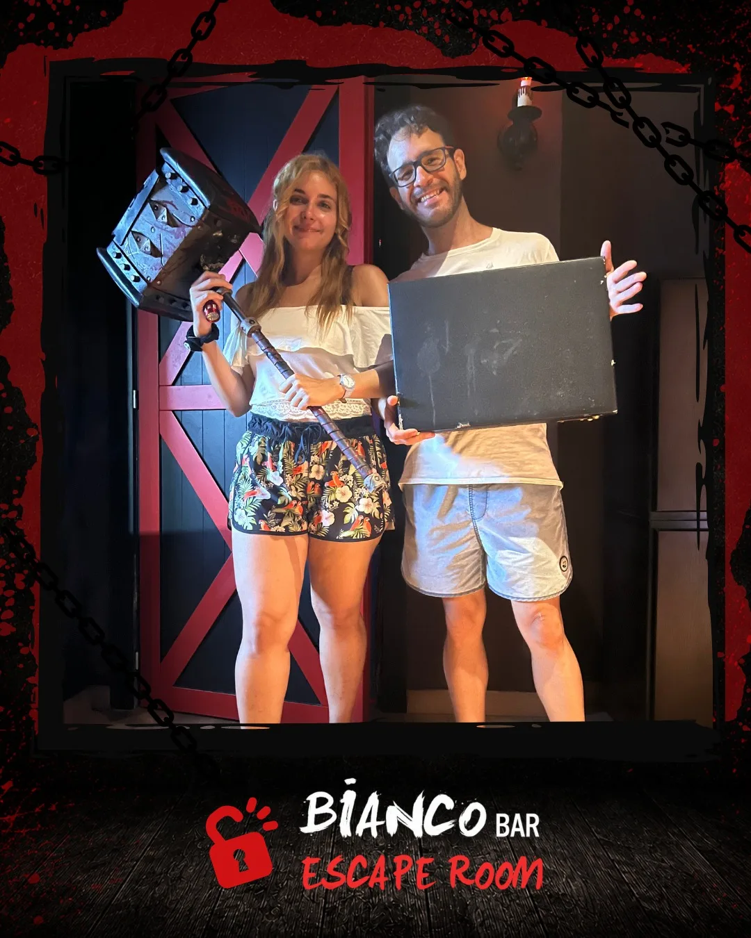 Dos jugadores posando sonrientes con atrezo de la sala tras escapar, ante la puerta roja del Bar Bianco